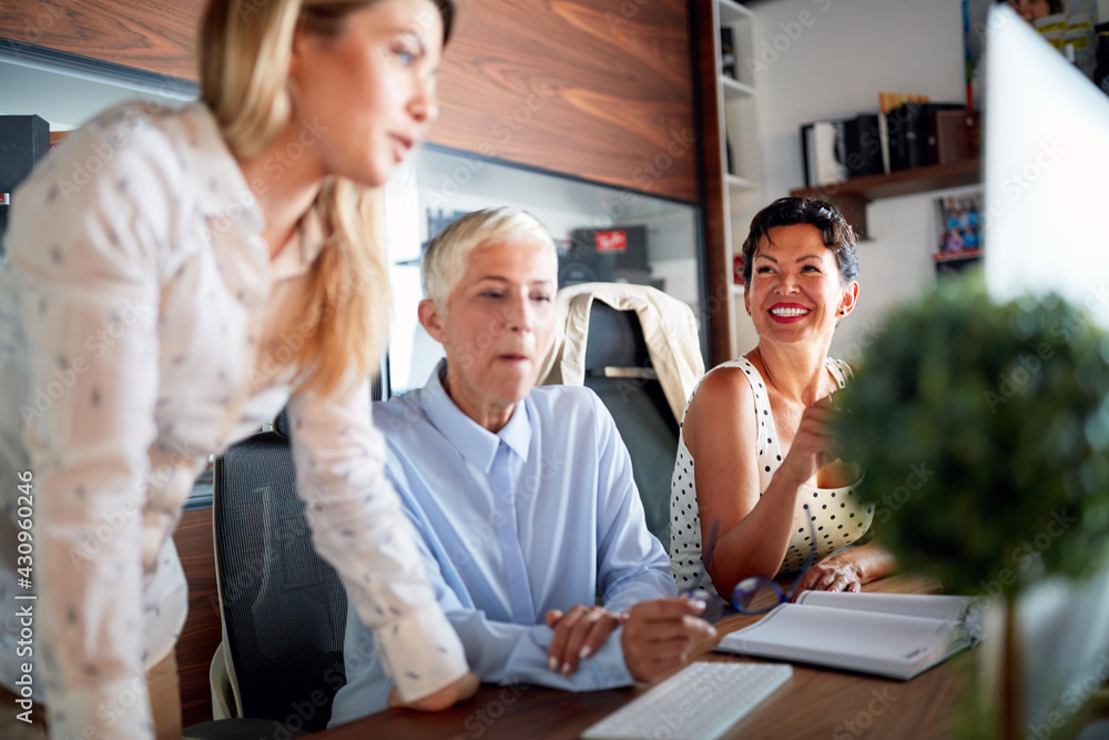 An elderly female boss is having a conversation with her female colleagues about a work they are doing together at workplace. Business, office, job An elderly female boss is having a conversation with her female colleagues about a work they are doing together at workplace. Business, office, job