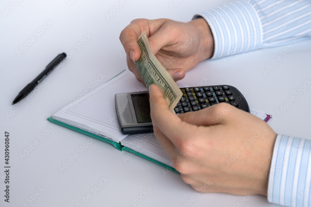 Men's hands with money, notepad, calculator and pen on a white background. Home finance. Financial accounting. Business concept. Close-up Men's hands with money, notepad, calculator and pen on a white background. Home finance. Financial accounting. Business concept. Close-up
