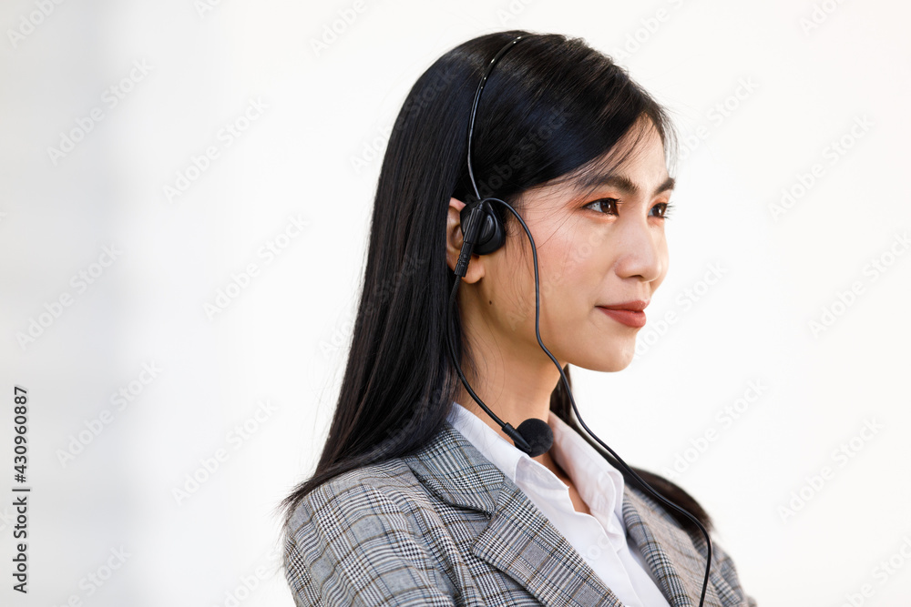 Portrait close-up shot of young pretty confident happy successful female asian businesswoman operator face with long black hair wear gray stripe suit and wired earphones with microphone on her head Portrait close-up shot of young pretty confident happy successful female asian businesswoman operator face with long black hair wear gray stripe suit and wired earphones with microphone on her head