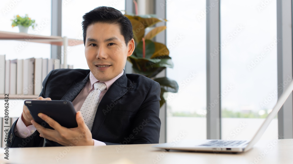 Confident Asian entrepreneur using tablet in office Confident Asian entrepreneur using tablet in office