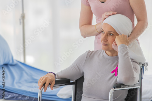 Fotografi A middle-aged breast cancer woman with clothing around her head effected from chemo therapy sitting on wheel chair and hold hand of her daughter with hope and trust in love