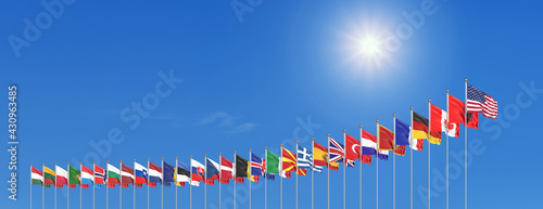 The 30 waving Flags of NATO Countries - North Atlantic Treaty. Isolated on sky background - 3D illustration.