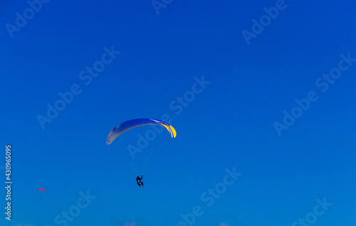 Paragliding in blue sky. Parachute with paraglider is flying. Extreme sports, freedom concept photo