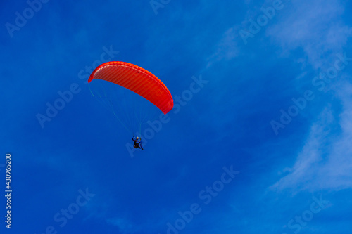 Paragliding in blue sky. Parachute with paraglider is flying. Extreme sports, freedom concept