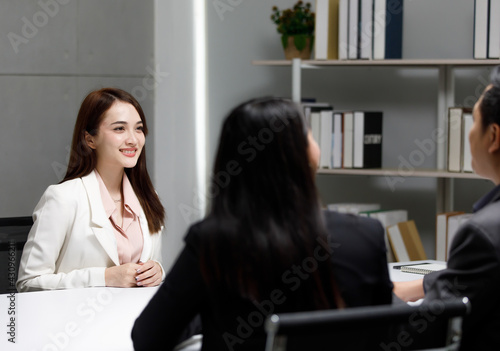 portrait of a young beautiful confident Asian woman wearing well-dressed sitting smiling and pay attention to the company interviewer in a human resources office. Focus on the applicant