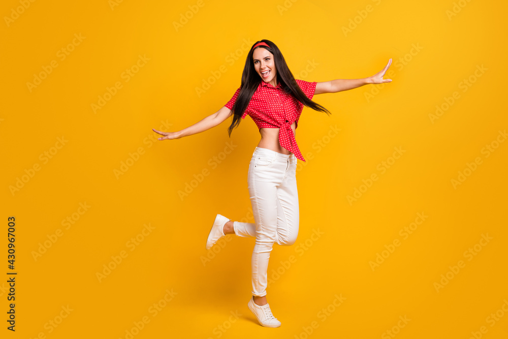Full length photo of cute shiny young lady wear red shirt dancing hands arms sides isolated yellow color background Full length photo of cute shiny young lady wear red shirt dancing hands arms sides isolated yellow color background