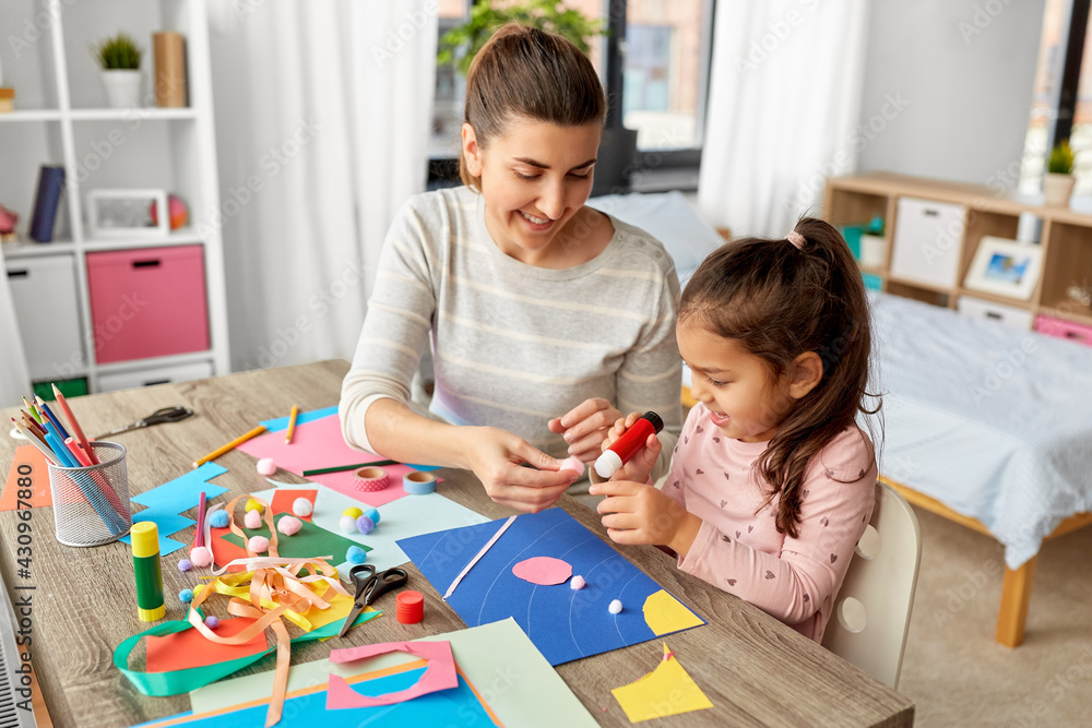 family, art and craft concept - mother spending time with her little daughter with glue making applique of color paper at home family, art and craft concept - mother spending time with her little daughter with glue making applique of color paper at home