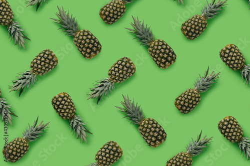 Fruit pattern with pineapples on green background. Minimal tropical food concept. Vegetarian vitamin diet trend. Exotic fruit texture. Flat lay, top view.