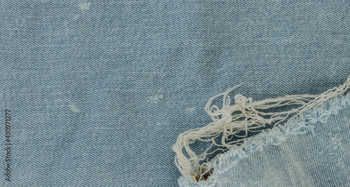 Fondo con textura de tejido vaquero en color azul claro con manchas blancas, desgastes y flecos photo