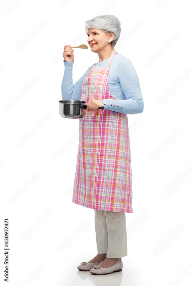 food cooking, culinary and old people concept - portrait of smiling senior woman in kitchen apron with pot and spoon over white background food cooking, culinary and old people concept - portrait of smiling senior woman in kitchen apron with pot and spoon over white background