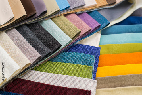 Samples of fabrics for upholstery, roman blinds. Multicolored fabric swatches spread out in a circle.