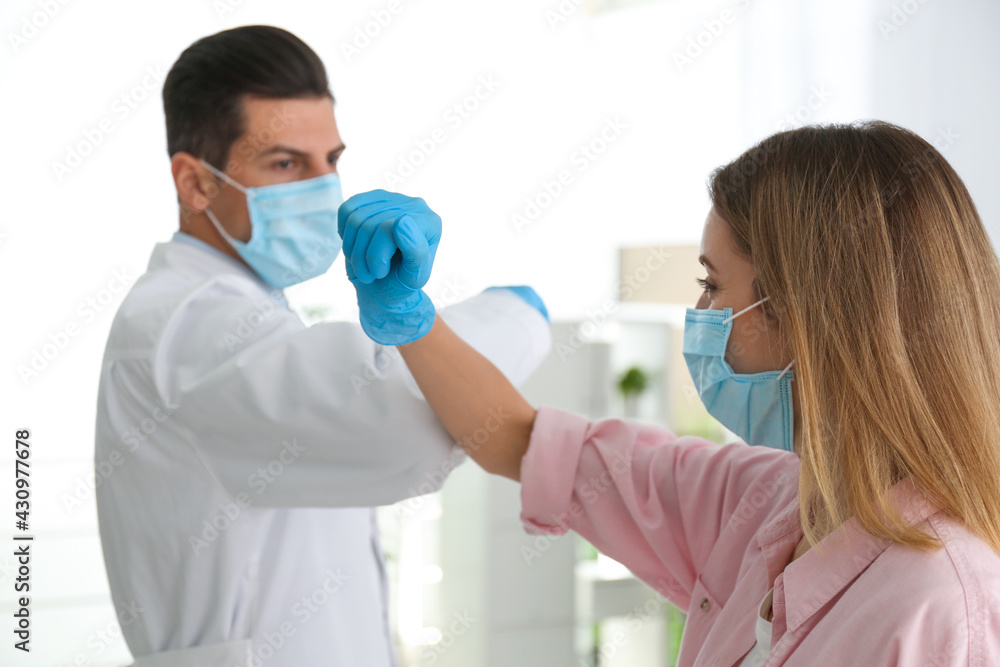 Doctor and patient doing elbow bump instead of handshake in clinic. New greeting during COVID-19 pandemic Doctor and patient doing elbow bump instead of handshake in clinic. New greeting during COVID-19 pandemic