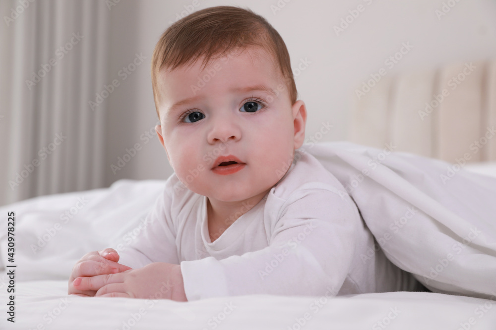 Cute little baby in bed under soft blanket indoors Cute little baby in bed under soft blanket indoors