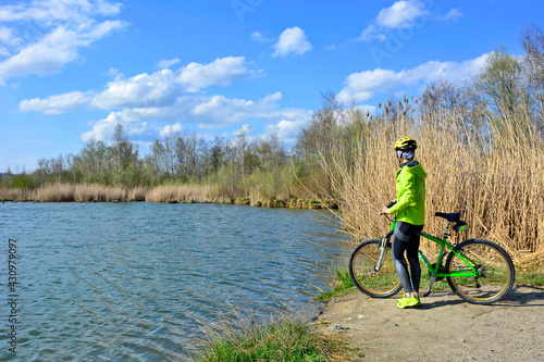 Woman with bicycle standing on shore of pond. Outdoor recreation, Stary Sacz, Poland