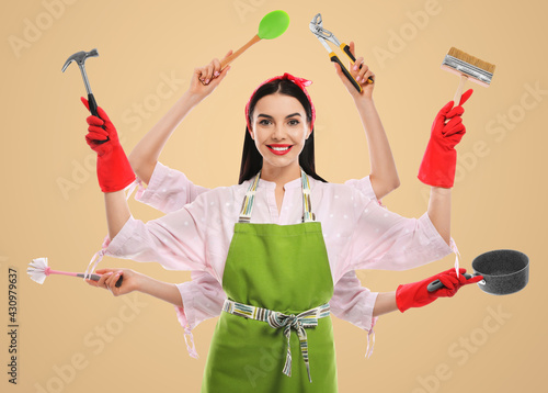 Multitask housewife with many hands holding different stuff on beige background photo