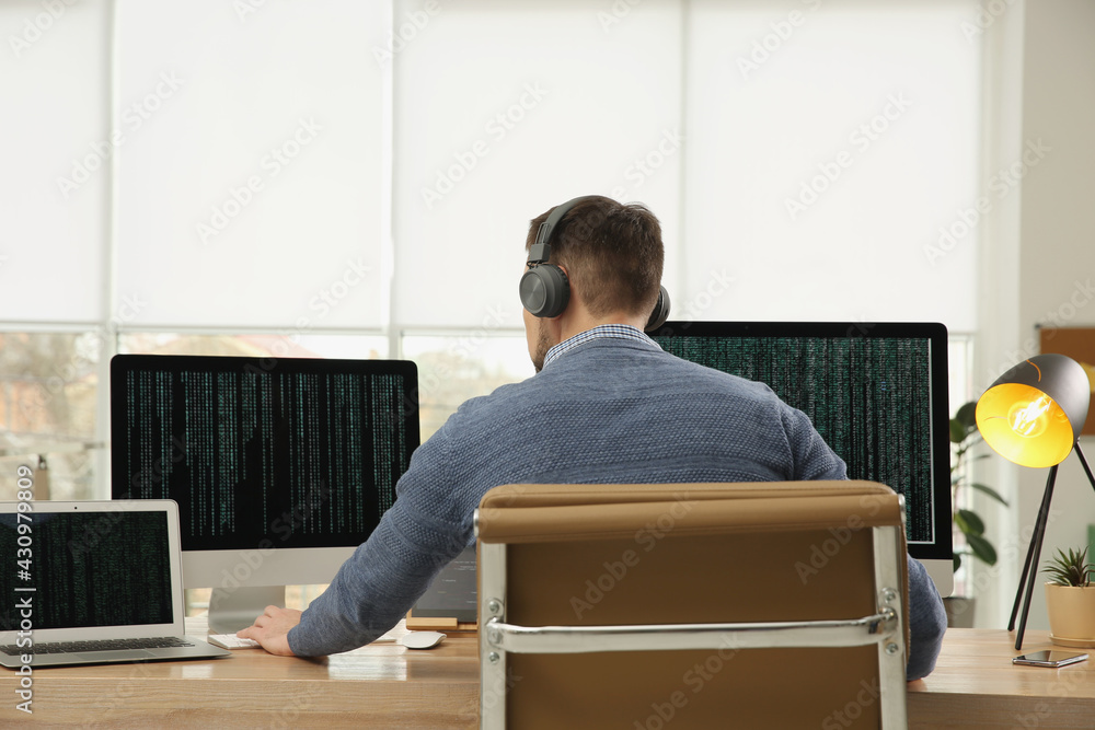 Programmer with headphones working at desk in office Programmer with headphones working at desk in office