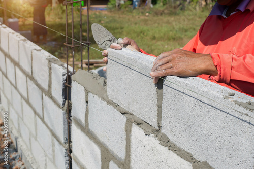masonry worker make concrete wall by cement block and plaster at construction site