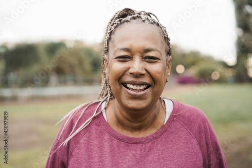 African senior woman smiling on camera outdoor in city park - Focus on face