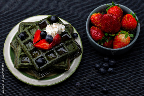 Green waffles with blueberries and strawberry