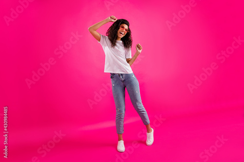 Full body photo of fancy young lady dance wear spectacles t-shirt jeans sneakers isolated on pink color background