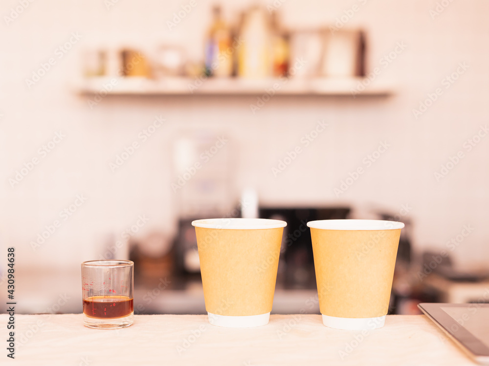 Two takeaway coffee cups and coffee measure cup are placing on coffee counter bar. Two takeaway coffee cups and coffee measure cup are placing on coffee counter bar.