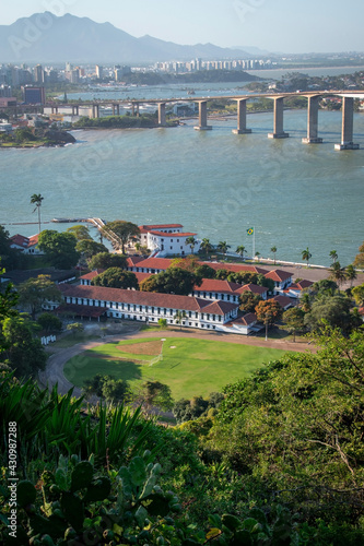 aerial view of a condominium building and a bridge over the sea with beach and tropical trees