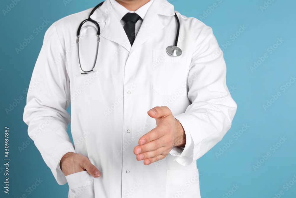 Doctor offering handshake on light blue background, closeup Doctor offering handshake on light blue background, closeup