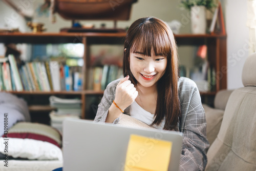 Happy young adult asian student woman study online via internet at home indoor on day.