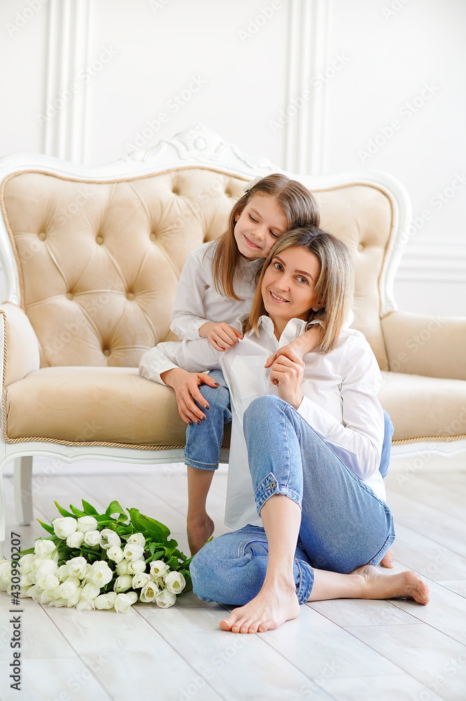 Obraz premium Portrait of little girl loving mother holding her and tulips