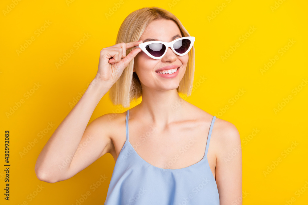 Photo of cheerful blond short hair lady look empty space wear spectacles blue top isolated on yellow color background Photo of cheerful blond short hair lady look empty space wear spectacles blue top isolated on yellow color background