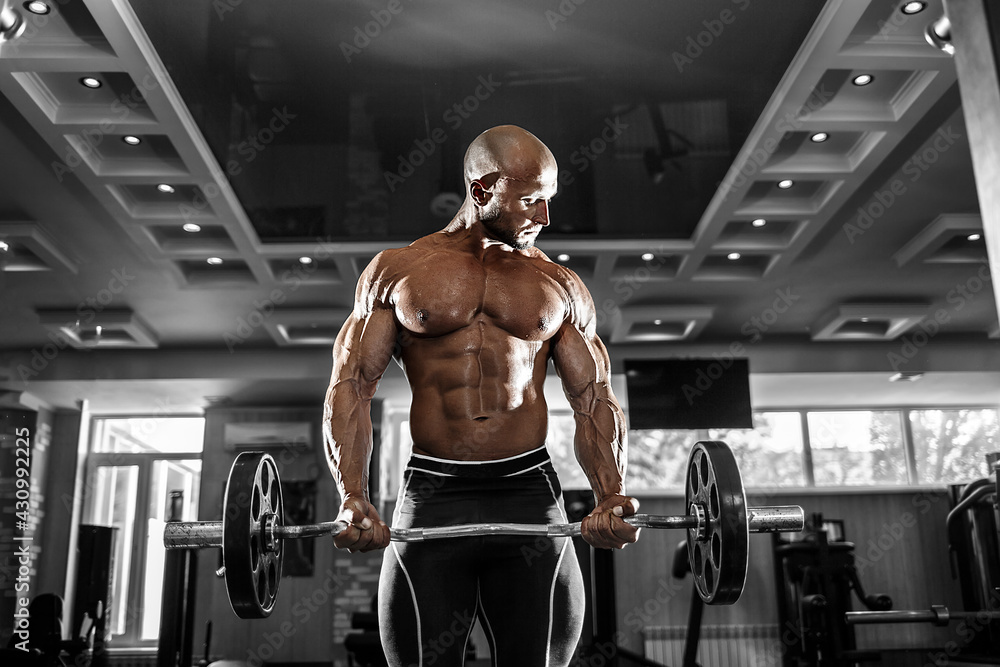 Muscular man working out in gym doing exercises with dumbbells at biceps, strong male naked torso abs Muscular man working out in gym doing exercises with dumbbells at biceps, strong male naked torso abs