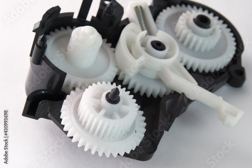 white plastic spur gears connected in one complex mechanism, part of the inkjet printer paper feeder mechanical drive