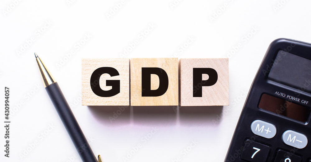 The word GDP is written on wooden cubes between a pen and a calculator on a light background. The word GDP is written on wooden cubes between a pen and a calculator on a light background.