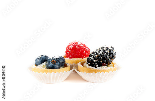 A group of mini tarts with berries isolated, delicious tiny cakes on white background,  small blueberry and raspberry cakes, sweet mini pies, gourmet dessert close-up 
