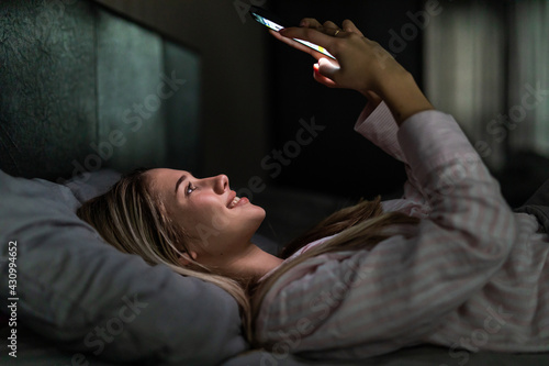 A Woman using smartphone on bed at night