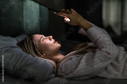 Woman using mobile phone in the dark in her bed
