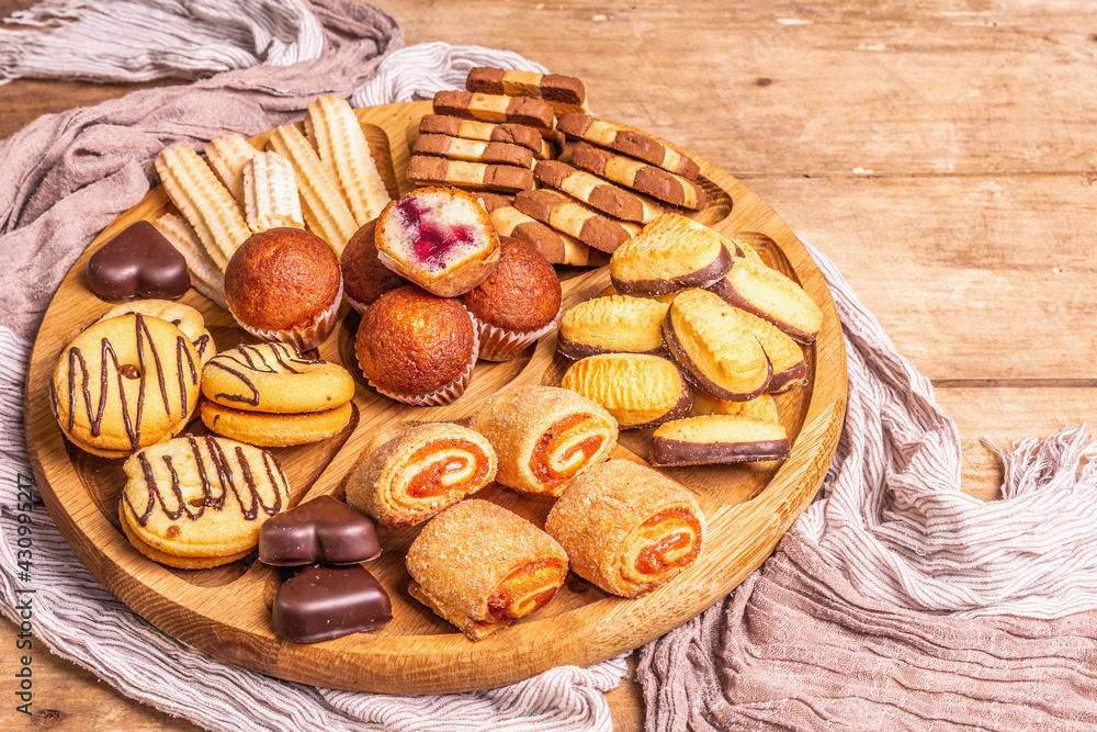 Assorted various cookies and muffins in wooden combination plate Assorted various cookies and muffins in wooden combination plate