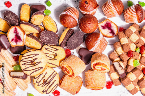 Quadro em tela Assorted various cookies and cupcakes scattered on wooden boards background