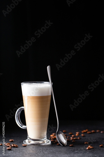 Foto coffee with milk, latte macchiato in a glass with a handle and a long spoon on a