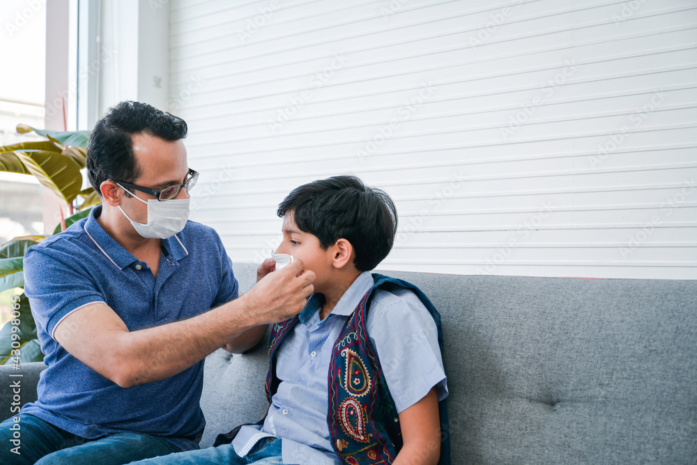 Indian father help his son wearing medical mask to protect Coronavirus covid-19 infected and he teach his son for the method to complete wearing the medical mask. Indian father help his son wearing medical mask to protect Coronavirus covid-19 infected and he teach his son for the method to complete wearing the medical mask.