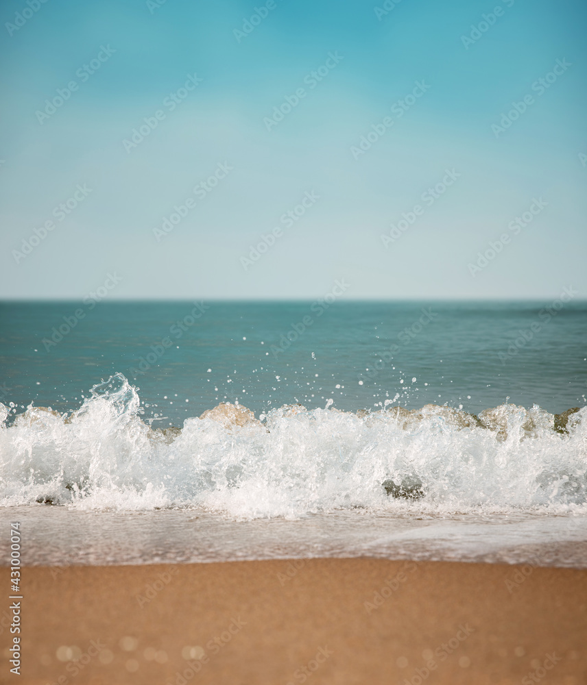 Sand Beach and Hard Wave on Summer Sunny Day. Blue Ocean and Sky as background. Low angle View. Focus on Water Ripple Swash