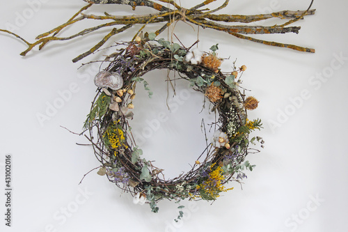 Decorative wreath of flowers and dried flowers with dry branches on the wall 