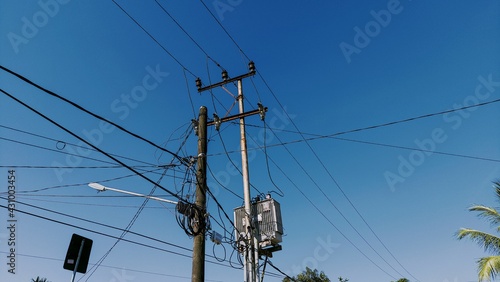 Electricity poles and lots of cables by the side of the road