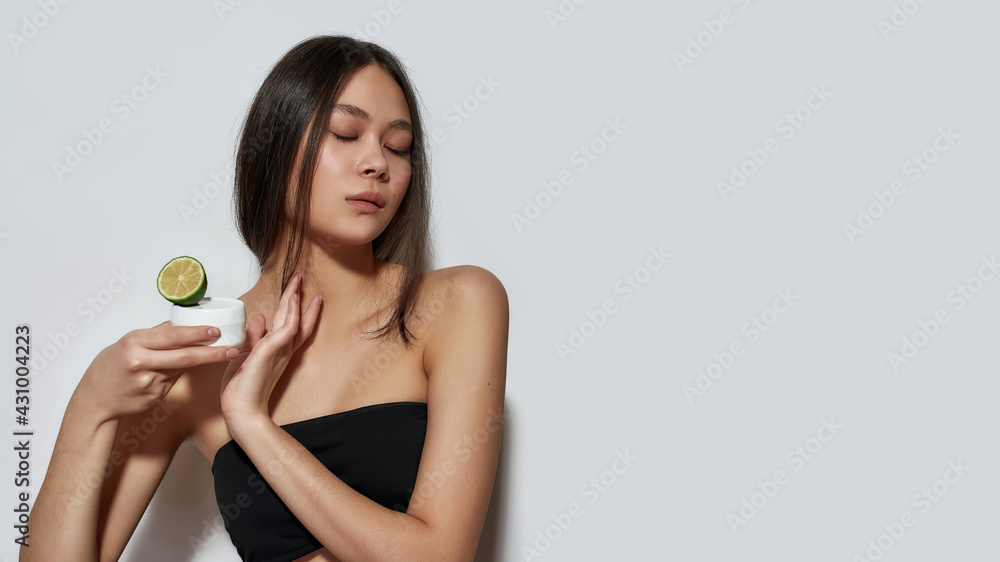Sensual asian woman holding citrus and cosmetology cream Sensual asian woman holding citrus and cosmetology cream