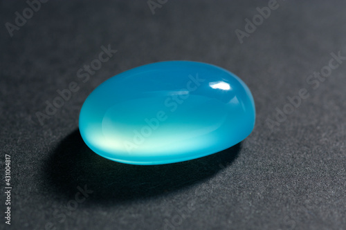 Natural baby blue chalcedony oval cabochon polished gemstone. Heated, color enhanced, increased saturation. Closeup photo. Microcrystalline, cryptocrystalline varietie of quartz. Waxy luster. photo