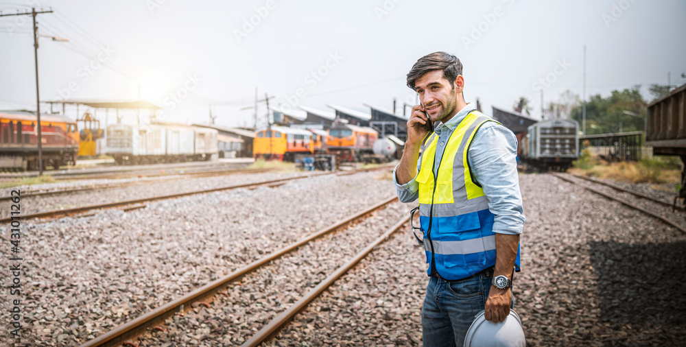 Caucasian man railway engineer use smartphone talking in the site work of train garage.	
