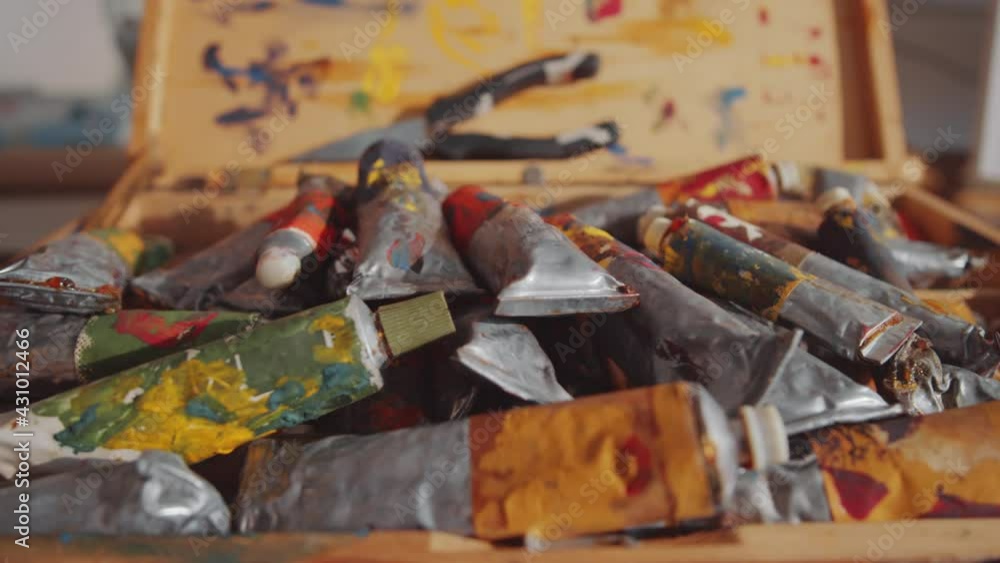 Close up handheld camera shot of oil paint tubes in wooden case in creative art studio Close up handheld camera shot of oil paint tubes in wooden case in creative art studio