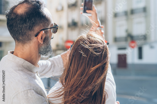 Adult couple outdoors using smartphone taking selfie photo