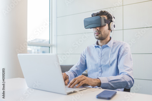 Canvas Print Young indian businessman using 3D viewer and computer
