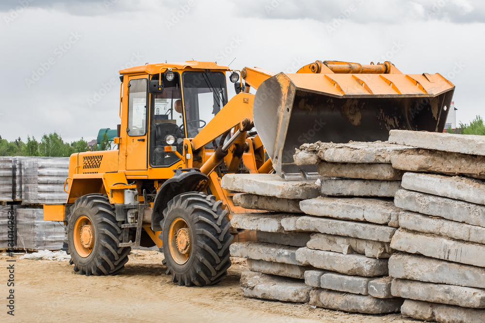 Bulldozer or excavator industrial heavy machine at a construction site unloads old concrete stone slabs material Bulldozer or excavator industrial heavy machine at a construction site unloads old concrete stone slabs material